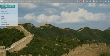 A Mac desktop showing the Apple menu dropdown, with System Settings highlighted.